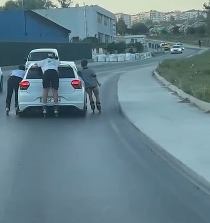 Otomobile tutunarak ilerleyen patenli çocuklar kamerada