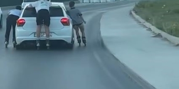 Otomobile tutunarak ilerleyen patenli çocuklar kamerada