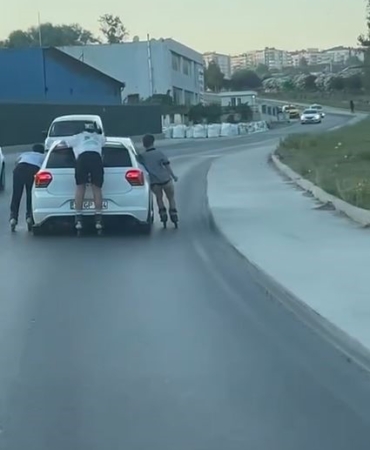 Otomobile tutunarak ilerleyen patenli çocuklar kamerada
