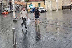 Taksim’de yağmur etkili oldu: Bir vatandaş yağmurdan kartonla korundu